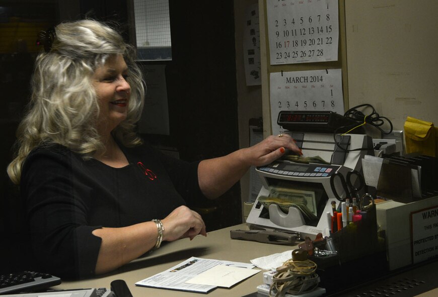 Brenda Kaziska, 20th Force Support Squadron non-appropriated funds central cashier, puts money through a bill counting machine at Shaw Air Force Base, S.C., Jan. 27, 2014. Kaziska takes multiple FSS deposits a week counting thousands of dollars, first by hand then by machine. (U. S. Air Force photo by Airman 1st Class Jensen Stidham/Released)
