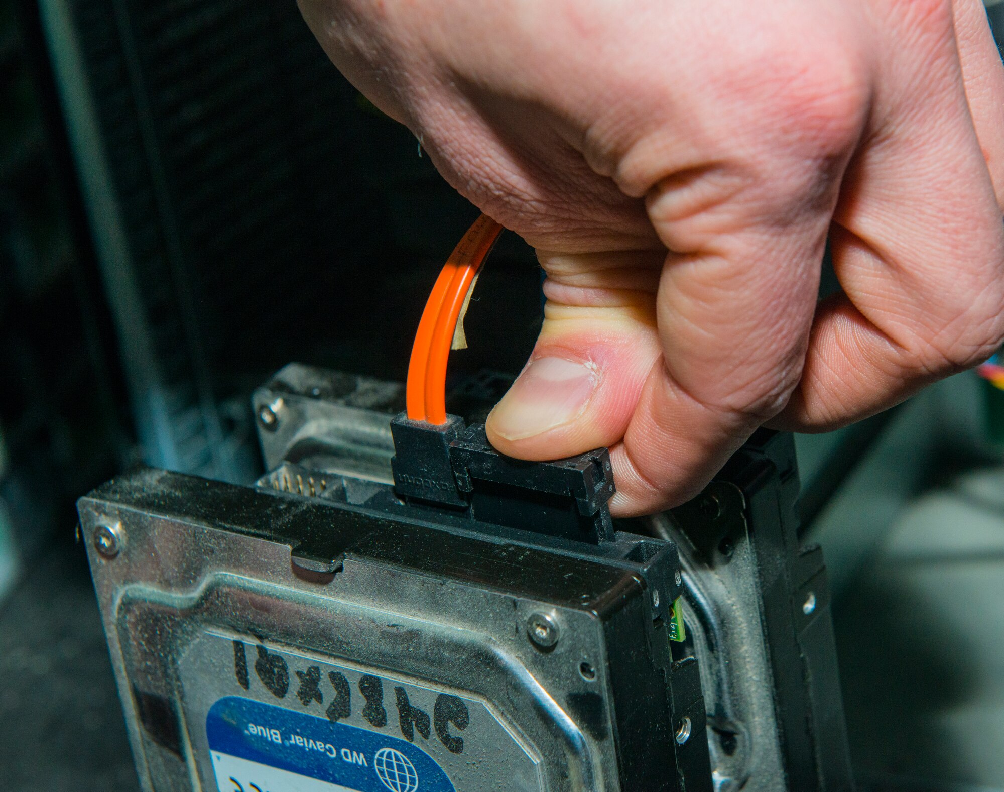 A 376th Expeditionary Communications Squadron help desk Airman plugs wires from a computer to a hard-disk drive to be able to read and then wipe what is on the drive Jan. 10, 2013, at the Transit Center at Manas, Kyrgyzstan.  The help desk Airmen have an average turnaround time of about 35 minutes per open ticket. (U.S. Air Force photo/Staff Sgt. Travis Edwards)