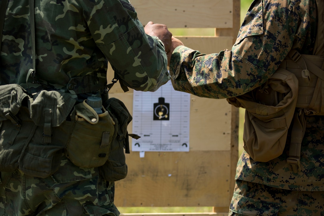 U.S. Marine Sgt. Michael Cox, right, and a Maldivian marine fist bump to acknowledge a good shot group during live-fire training on Maafilaafushi, Maldives, Jan. 25, 2014. 