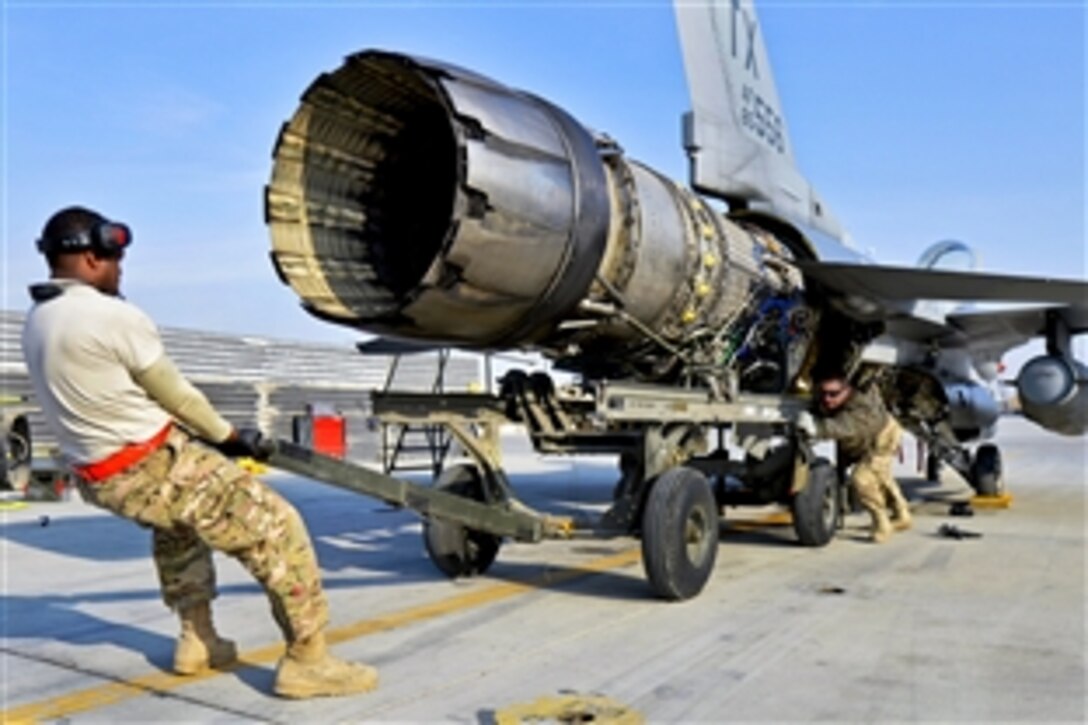 U.S. airmen work to remove the engine from an F-16 Fighting Falcon aircraft on Bagram Airfield, Afghanistan, Jan. 22, 2014.