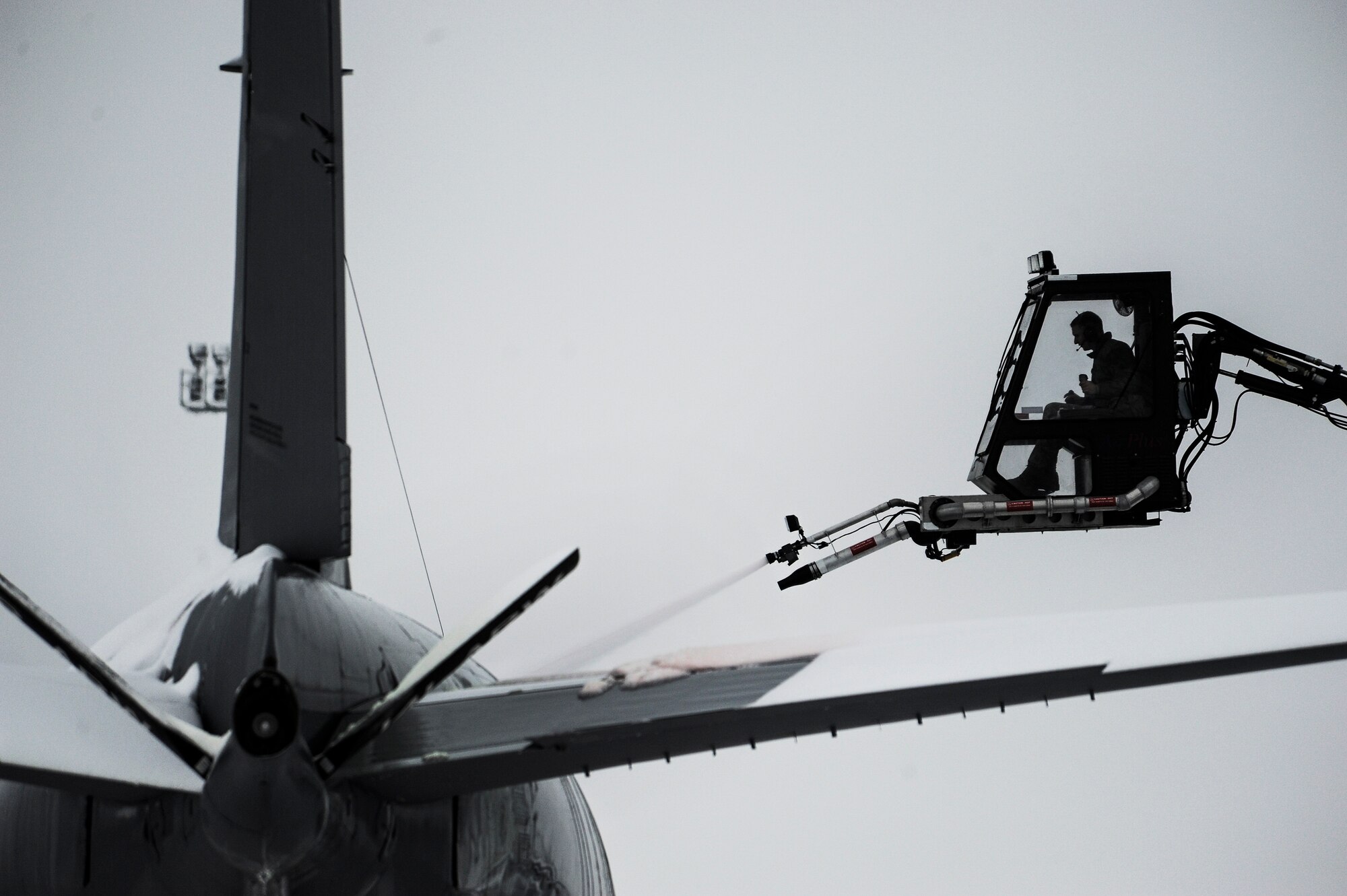 A 92nd Aircraft Maintenance Squadron crane operator de-ices a KC-135 Stratotanker on the flight line for flight preparation at Fairchild Air Force Base, Wash., Jan. 29, 2014. Aircraft de-icing is a process in which liquid solutions are sprayed onto an aircraft during the winter to both defrost and prevent future precipitation from freezing. Snow and ice on the wings and rear tail component change their shape and disrupt the airflow making it difficult to fly and diminishes fuel economy.(U.S. Air Force photo by Staff Sgt. Alexandre Montes/ RELEASED)