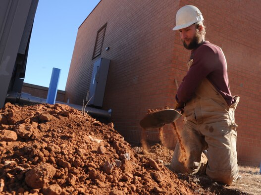 Derek Engle, a PAE laborer, digs a trench in search of water pipes for a project that will upgrade the current heating, ventilation and air conditioning system in the unaccompanied officers’ quarters. The $2 million project, which began earlier this month, is scheduled for completion this August. (U.S. Air Force photo/ Senior Airman Frank Casciotta)
