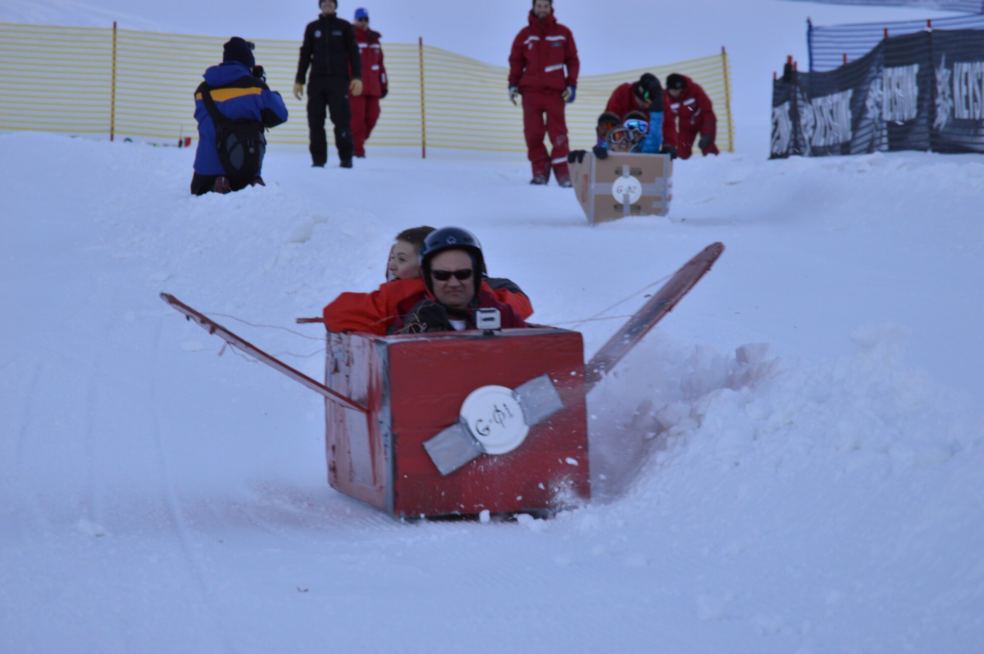 Col. David Gibson and Grant Sparkman slide down the cardboard derby race course Jan. 25 during the 24th annual SnoFest. The team from the Academy Dean of Faculty's computer science department took first place in the group category for fastest snow craft. (U.S. Air Force Photo/Patrice Clarke)