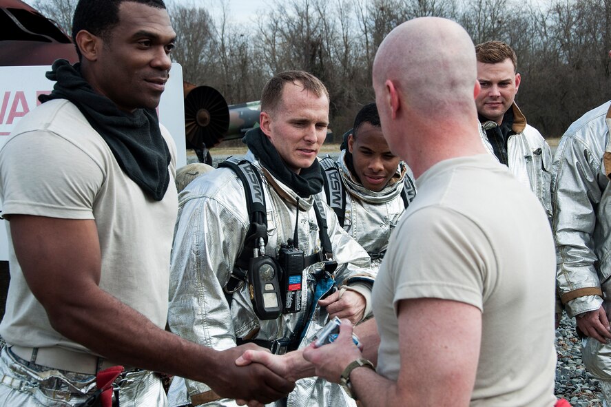 U.S. Air Force Col. Jonathan Ellis, 307th Bomb Wing commander, thanks and awards coins to a team of firefighters assigned to the 307th Civil Engineer Squadron following a training scenario on Jan. 26, 2014, Barksdale Air Force Base, La. Ellis donned firefighting gear and joined the team to help extinguish a fire inside of a large frame aircraft trainer. (U.S. Air Force photo by Tech. Sgt. Theodore Daigle/Released)
