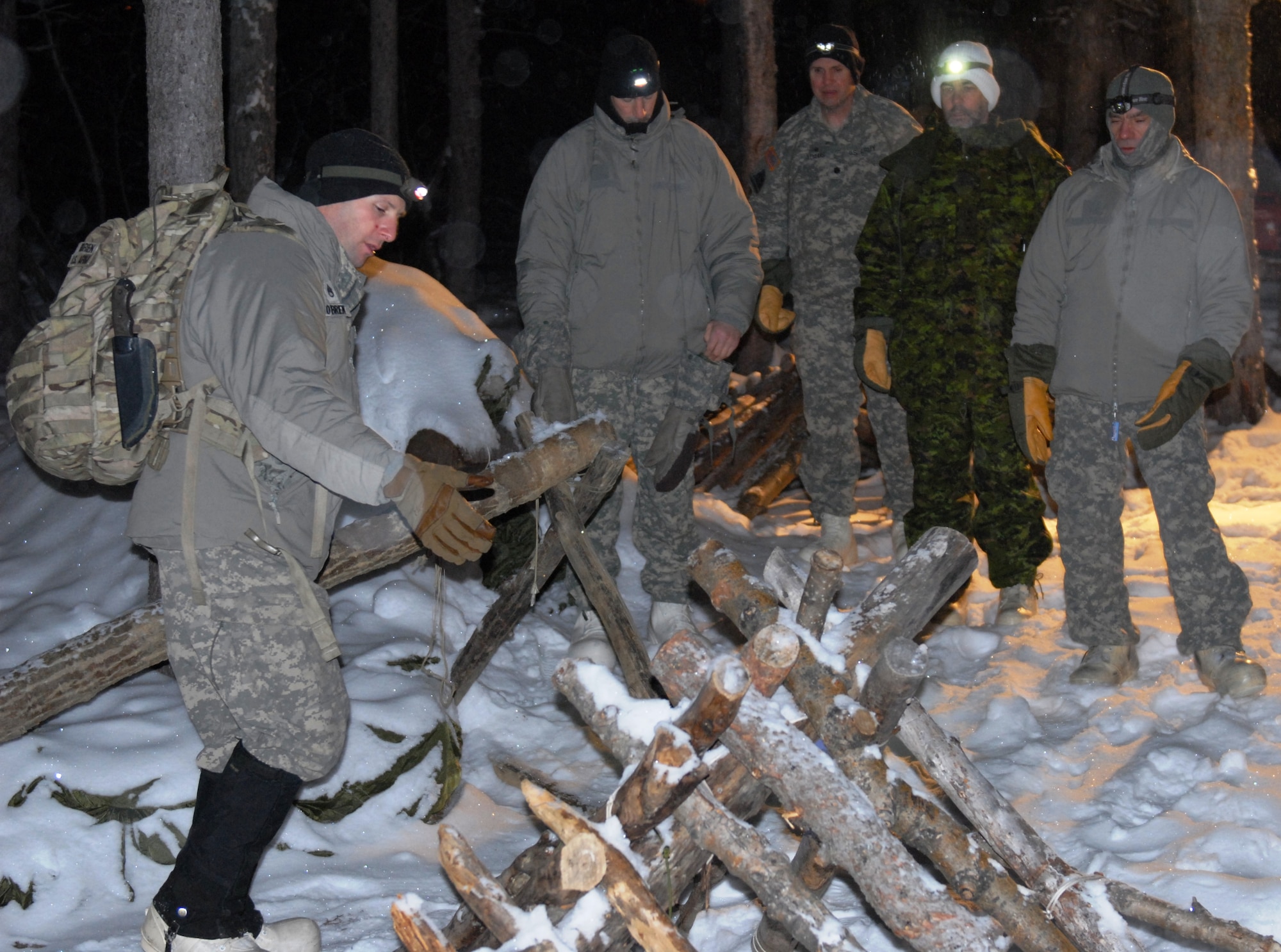 BLACK RAPIDS TRAINING SITE, Alaska— U.S. Army Staff Sgt. Michael Obrien (left), U.S. Army Alaska Northern Warfare Training Center projects NCO and instructor, provides instruction on how to build an Arctic thermal shelter during an Arctic survival training class Jan. 10. Alaskan Command/Joint Task Force-Alaska and USARAK hosted an Arctic General Officer/Flag Officer Conference Jan. 7-11, which included distinguished guests from the U.S. Air Force, U.S. Army, Alaska National Guard, U.S. Coast Guard and Canadian Forces, to strengthen partnerships, discuss future Arctic challenges and joint capabilities. (U.S. Army photo/CPT Patrick Sawicki)