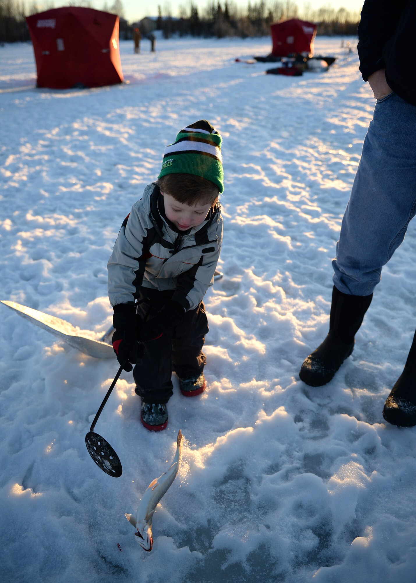 Mason, son of Capt. Bryan Sixkiller, plays with an Arctic Char after it was caught during an ice fishing day at Moose Lake, Eielson Air Force Base, Alaska, Jan. 25, 2014. Families were encouraged to get out on the ice and enjoy unseasonably warm weather while promoting resiliency through outdoor activities. (U.S. Air Force photo by Senior Airman Shawn Nickel)