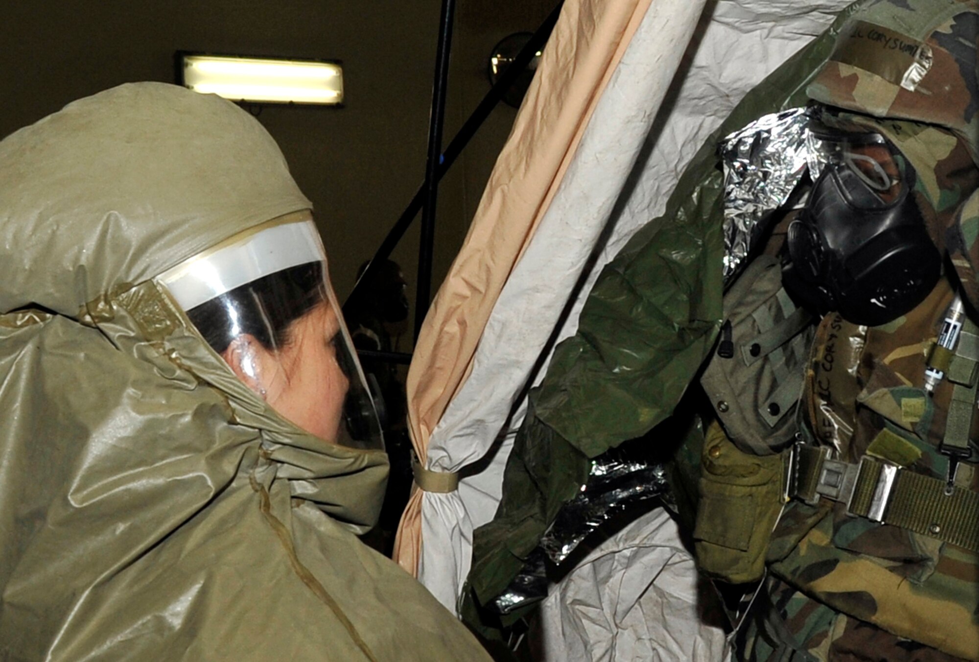 Airman 1st Class Kiani Montecillo, 35th Medical Group, helps Airman 1st Class Cory Sumter, 35th Communications Squadron, process through the decontamination area at Misawa Air Base, Japan, Jan. 28, 2014. While performing a post attack reconnaissance sweep, Sumter was contaminated by a simulated chemical attack and had to report to the 35 MDG to be decontaminated. (U.S. Air Force photo/Airman 1st Class Zachary Kee)