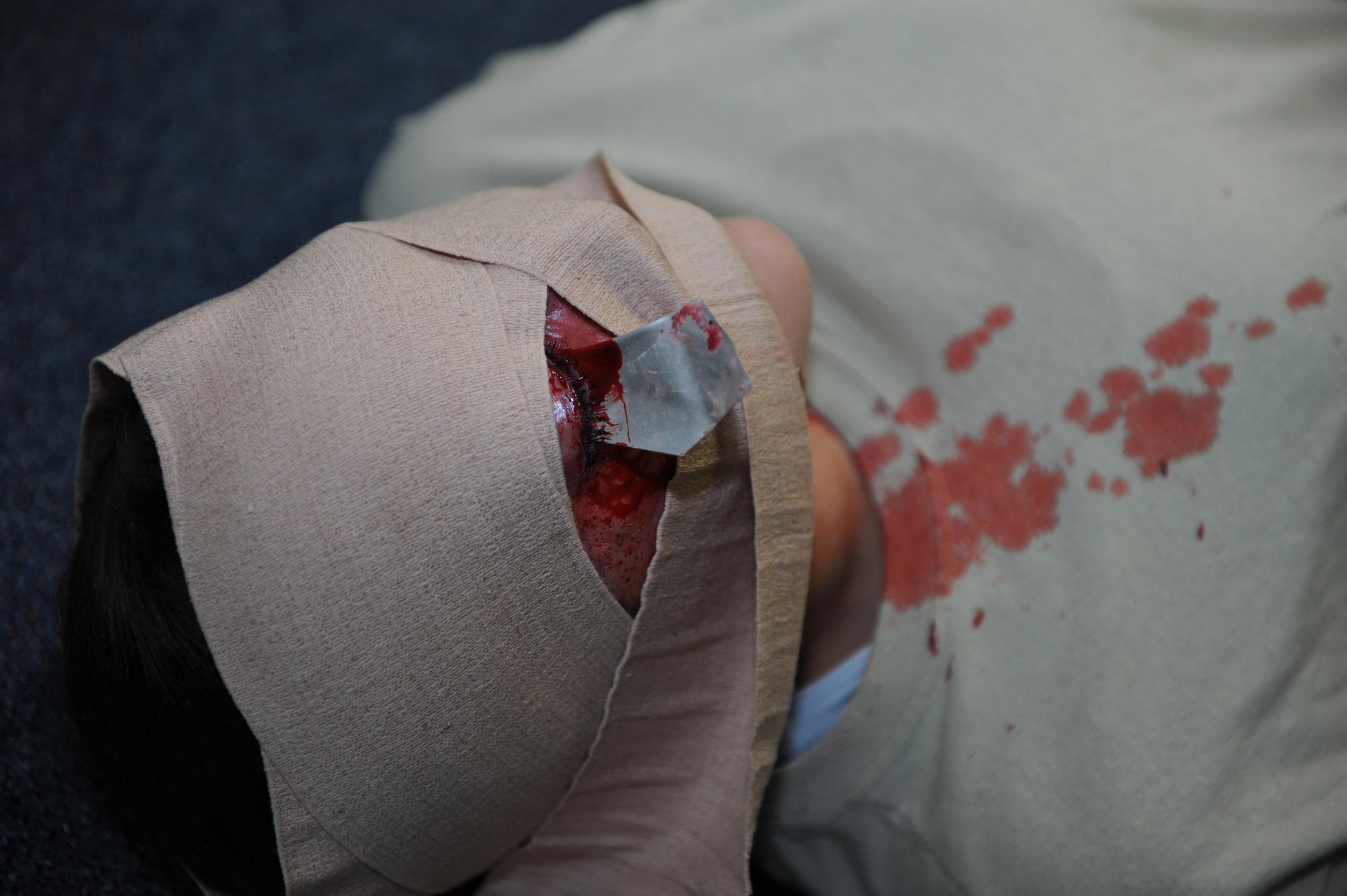 A victim with a simulated eye wound waits for self-aid and buddy care during a Mission Focused Exercise on Kadena Air Base, Japan, Jan. 29, 2014. Self-aid and buddy care encompasses basic life support and limb-saving techniques to help wounded or injured personnel survive in medical emergencies until medical help is available. (U.S. Air Force photo by Airman 1st Class Hailey R. Staker) 
