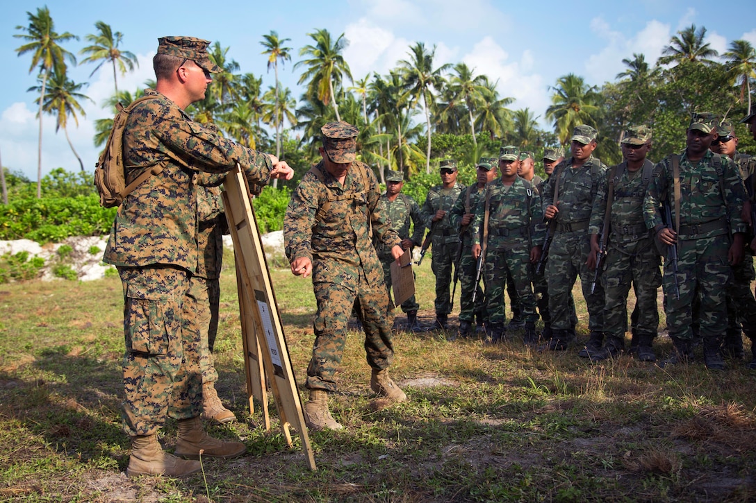 U.S. Marines discuss shooting techniques with Maldivian marines before live-fire training on Maafilaafushi, Maldives, Jan. 28, 2014. The U.S. Marines are assigned to Mobile Training Team, U.S. Marine Corps Forces Pacific. This noncommissioned officer development program creates a setting for professional military and cultural exchanges. It also gives both forces an opportunity to train in unfamiliar settings, gaining experience with different tactics, techniques and procedures. 