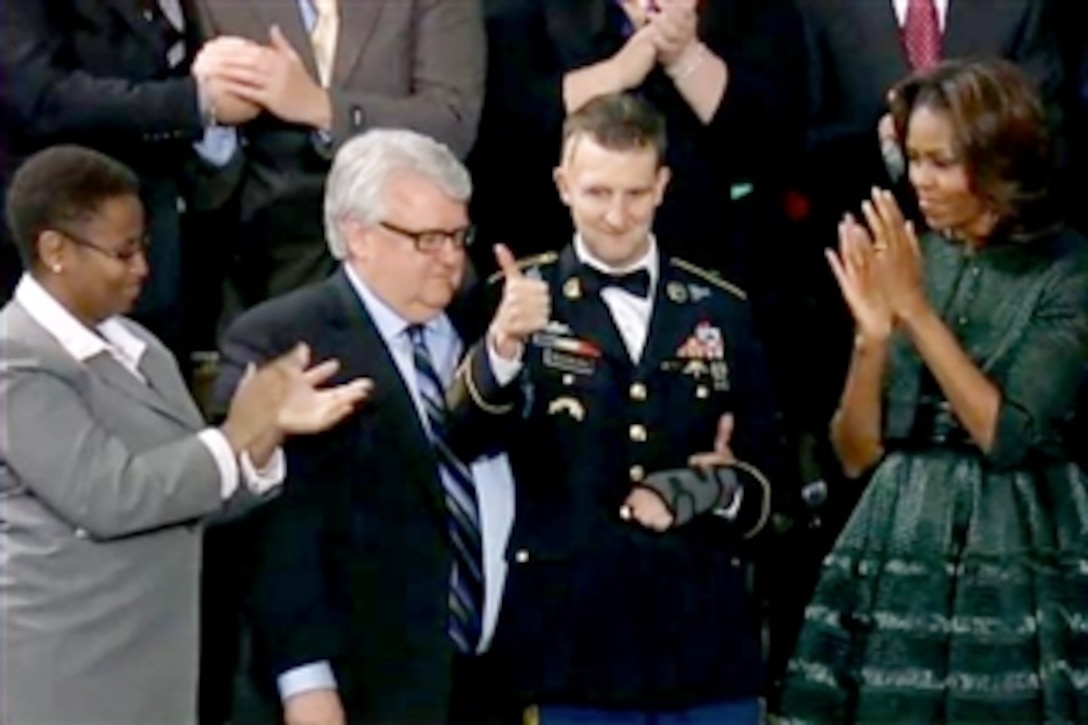 Army Sgt. 1st Class Cory Remsburg, who was wounded by a bomb blast in Afghanistan on his 10th deployment, gives a thumbs up to the audience, which applauded after President Barack Obama cited him during the State of the Union address, Jan. 28, 2014. Remsburg was a guest in First Lady Michelle Obama's box during the speech. 
