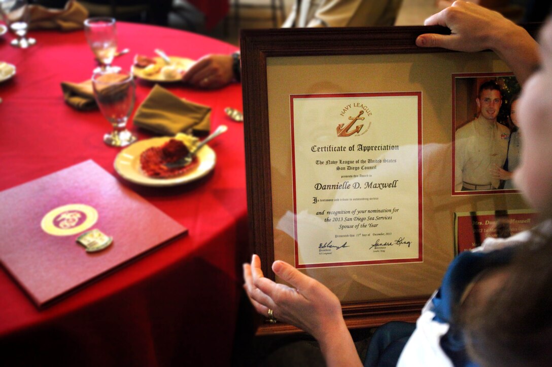 Dannielle Maxwell, wife of Gunnery Sgt. Dustin Maxwell, Landing Support Company Gunnery Sergeant, Combat Logistics Regiment 17, 1st Marine Logistics Group, looks at a plaque she received during a Family Readiness luncheon, honoring her and several other 2013 1st MLG Spouse of the Year award candidates, aboard Camp Pendleton, Calif., Jan. 24, 2014. The lunch recognized all the volunteer spouses within 1st MLG.