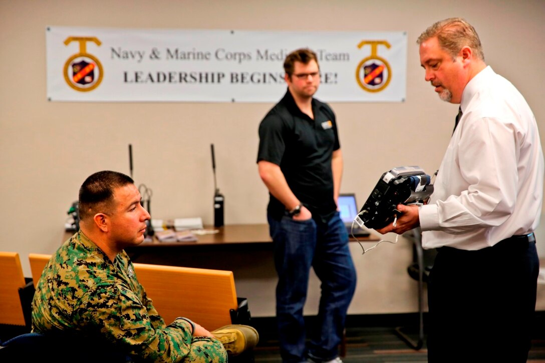 Marc Whedbe, director of U.S. military sales for Remote Diagnostic Technologies, from Virginia Beach, Va. talks to Marines and Sailors about the Tempus Pro, a tactical telemedicine device, over two days of informational and operational testing aboard Camp Pendleton, Calif., Jan. 22-23. The Tempus Pro attaches to the patient and broadcasts their vital signs back to a battalion aid station or aiding physician so that they can instruct and help the corpsman.