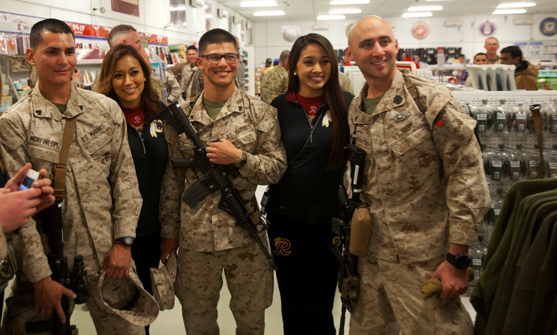 Washington Redskins cheerleaders pose for a photo with service members during a visit to support the troops aboard Camp Leatherneck, Afghanistan, Jan. 28, 2014. To show their appreciation for those serving in support of Operation Enduring Freedom, they personally autographed several calendars starring the cheerleaders and posed for photographs with service members. (U.S. Marine Corps photo by Cpl. Cody Haas/ released)