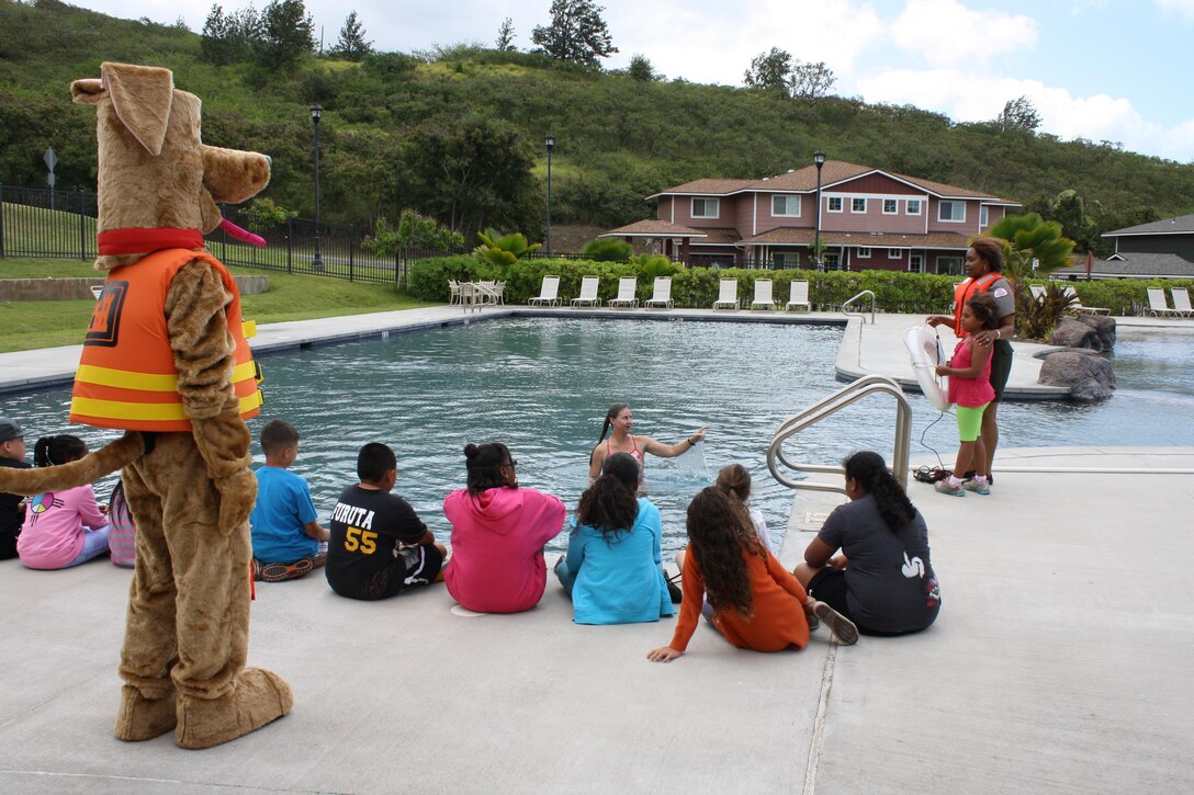 Bobber the Water Safety Dog watches as Corps of Engineers Park Ranger Angela Jones and Honolulu District employee Debbie Solis (in pool) demonstate water safety rescue techinques to Fort Shafter Elementary School students during a water safety presentation at the Fort Shafter community center pool. 