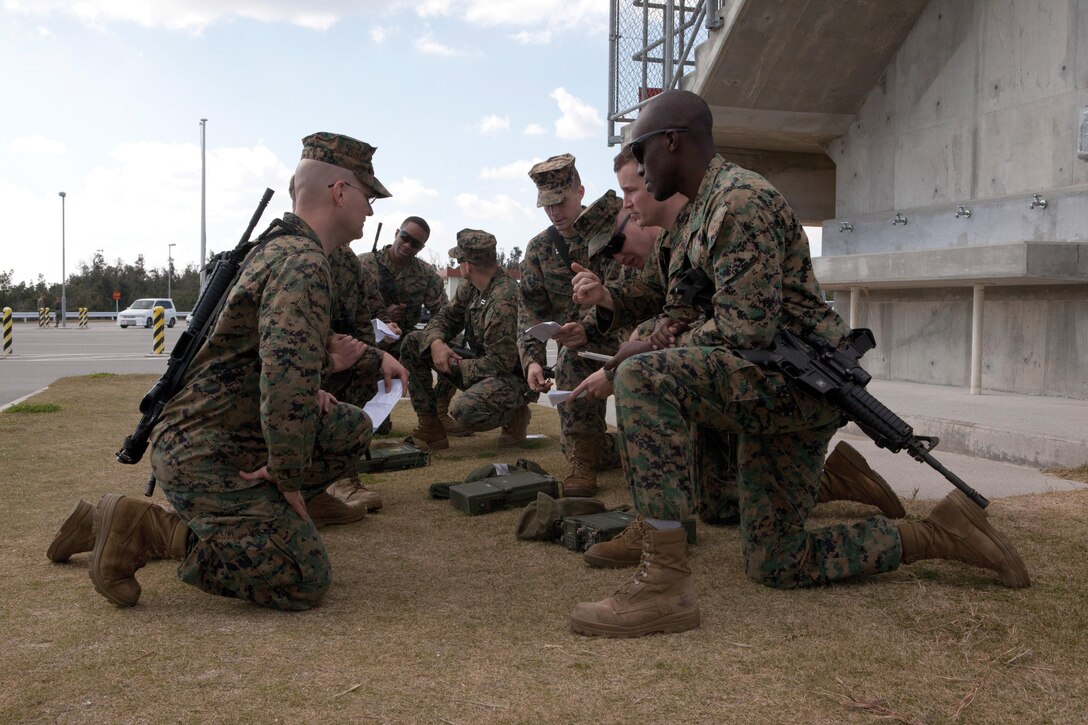 A squad receives instruction on assembling the PRC-117 radio during the battalion super-squad competition Jan. 23 at Range 15 on Camp Hansen. Camp Hansen’s afternoon events consisted of a two-mile hike, an Intermediate Combat Rifle Marksmanship live-fire, a memory exercise, and assembly of a radio to transmit a medical evacuation request. The Marines are legal service specialists representing H&S Bn., Legal Services section.