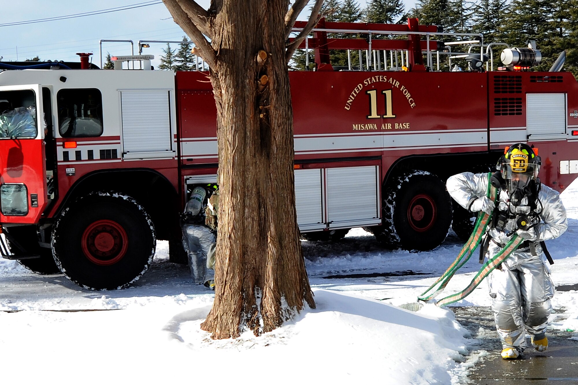 Firefighters from the 35th Civil Engineer Squadron rush hundreds of feet of hose into a burning building to stifel the flames during Phase II of the operational readiness exercise on Misawa Air Base, Japan, Jan. 29, 2014. Firefighters have to make sure the hose they are using is the correct length prior to entering the burning building to ensure no rooms are missed when clearing. (U.S. Air Force photo/Tech. Sgt. April Quintanilla)