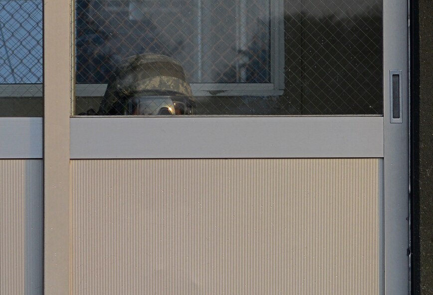 U.S. Air Force Senior Airman Jeremy Johnson, 35th Security Forces senior force protector, takes cover in the guard shack during an operational readiness exercise at Misawa Air Base, Japan, Jan. 28, 2014. While under attack, 35 SFS protectors take cover and radio in the location of the attacker to the law enforcement desk before perusing the attacker. (U.S. Air Force photo/Tech. Sgt. April Quintanilla)