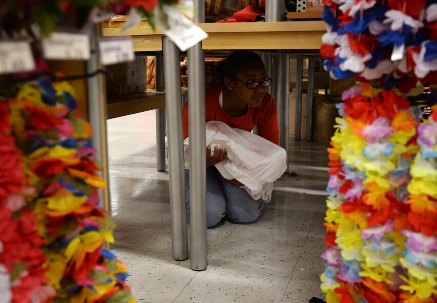 Tech. Sgt. Nakeysha Saddler, 15th Medical Group, hides under a display with her simulated baby during a Joint Exercise Evaluation Training Team active shooter exercise at Joint Base, Pearl Harbor-Hickam, Hawaii, Jan. 29, 2014. The medical group provided Airmen who acted as casualties of the active shooter incident. The training enhanced first responder capabilities, and improved security communication and coordination between Hickam and Pearl Harbor. (U.S. Air Force photo/Staff. Sgt. Alexander Martinez)