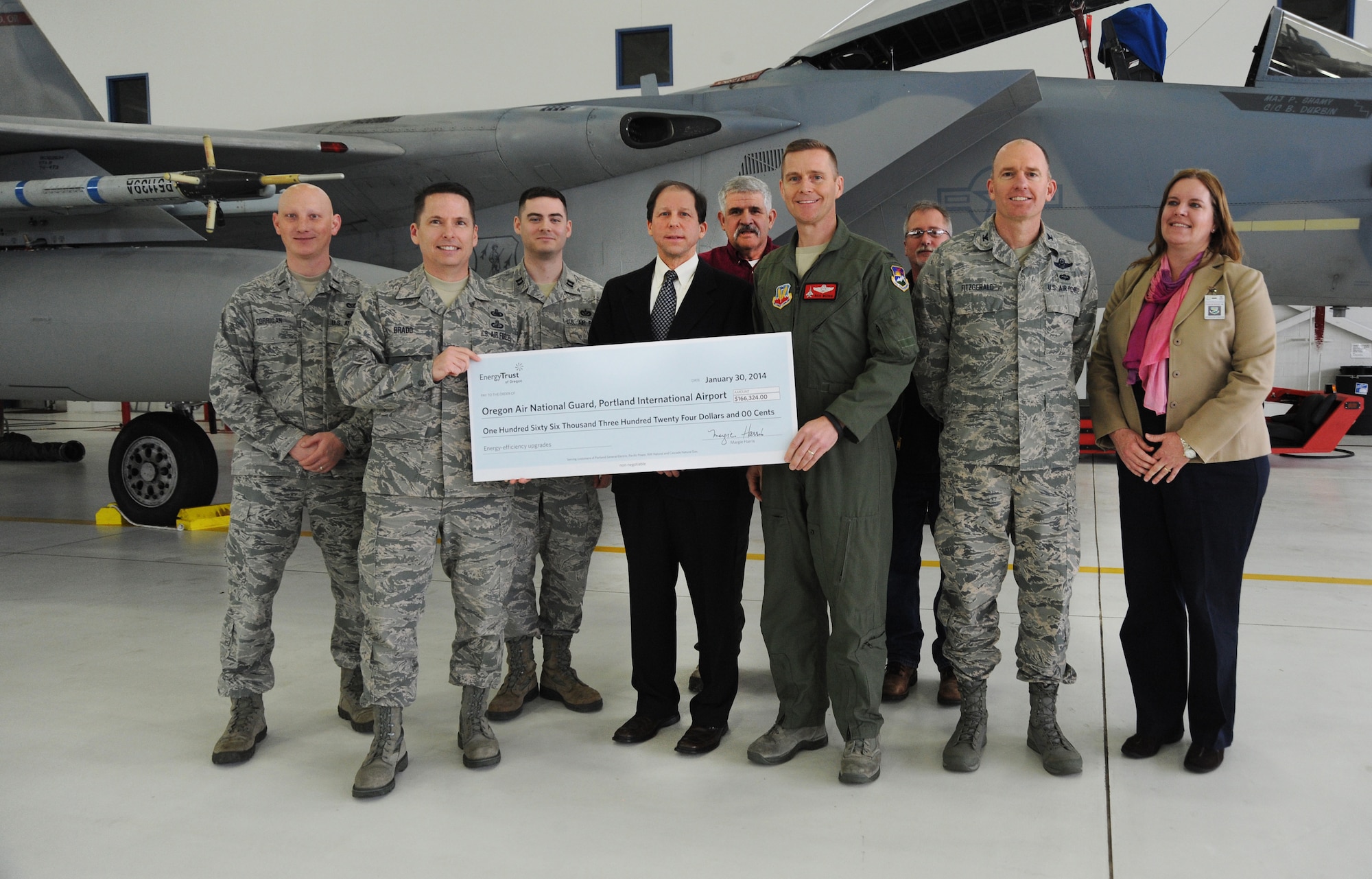 Oregon Air National Guard Chief Master Sgt. Loren Bradd and Col. Rick Wedan, 142nd Fighter Wing Commander, hold a rebate check with Paul West, Director of Energy Programs, and pause for a photograph with other Oregon Air National Guard members, Portland Air National Guard Base staff and other Energy Trust staff during a presentation ceremony held at the Portland Air National Guard Base, Ore., Jan. 30, 2014. (Air National Guard photo by Tech. Sgt. John Hughel, 142nd Fighter Wing Public Affairs/Released)