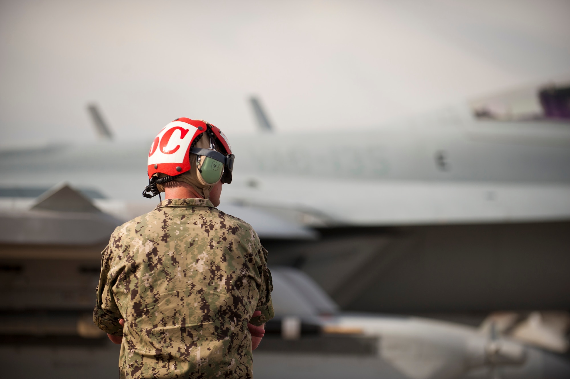 An aircraft maintainer from the 135th Electronic Attack Squadron, Naval Air Station Whidbey Island, Wash., watches as his assigned aircraft passes by for a training mission after pre-flight checks Jan. 29, 2014, at Nellis Air Force Base, Nev. Joint service aircrews play their part in “Blue Force” operations, supporting the simulated air-war against “Red Forces” organized by the 57th Adversary Tactics Group. (U.S. Air Force photo by Airman 1st Class Joshua Kleinholz)