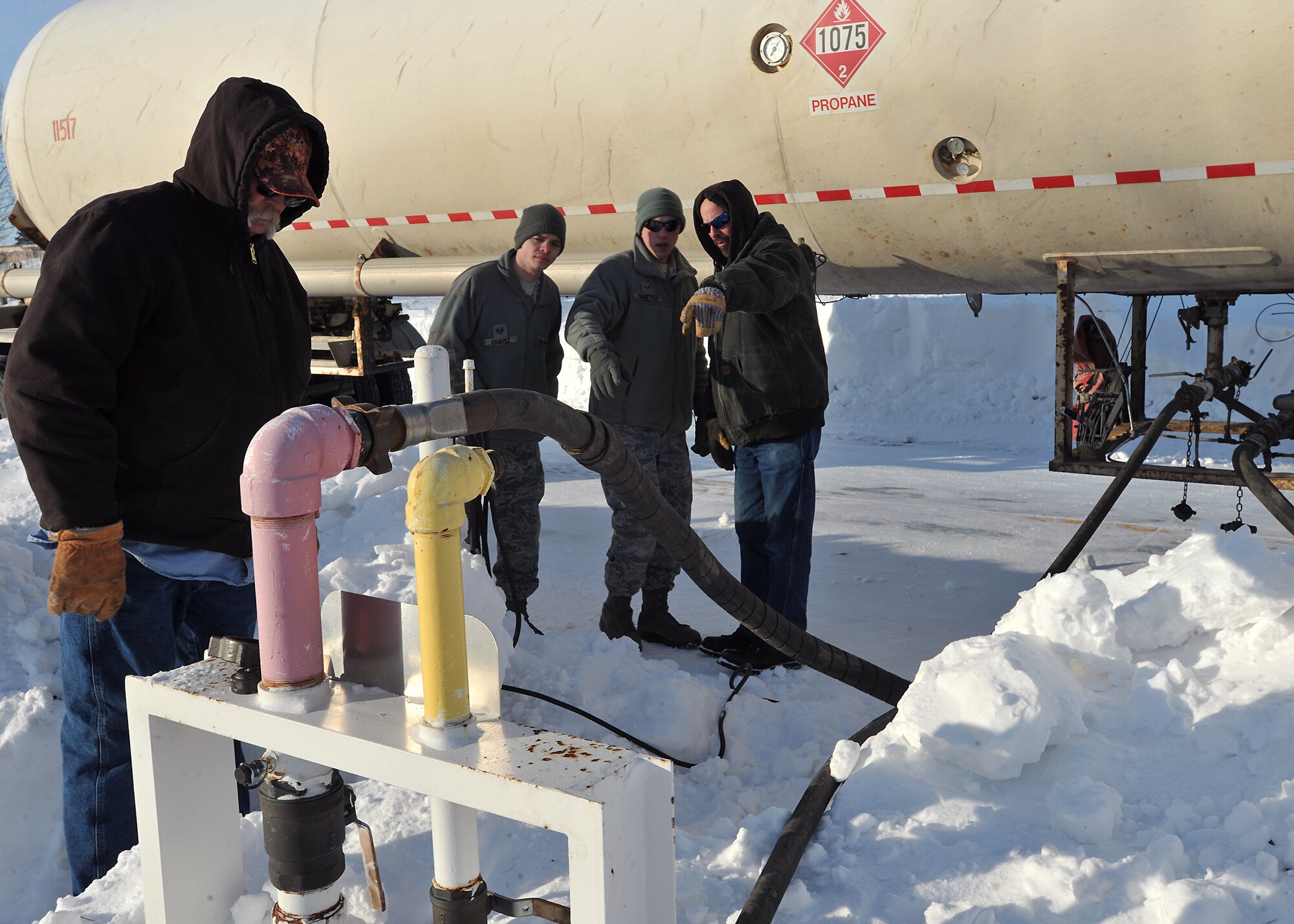 Members of the 319th Civil Engineer Squadron heat ventilation and airconditioning shop discuss how to attach a hose to the base’s synthetic natural gas farm pipeline, Jan. 27, 2014 on Grand Forks Air Force Base, N.D. The 319th CES contributed over ninety after duty work hours to ensure the base’s heating supply was consistent. (U.S. Air Force photo/Senior Airman Xavier Navarro)