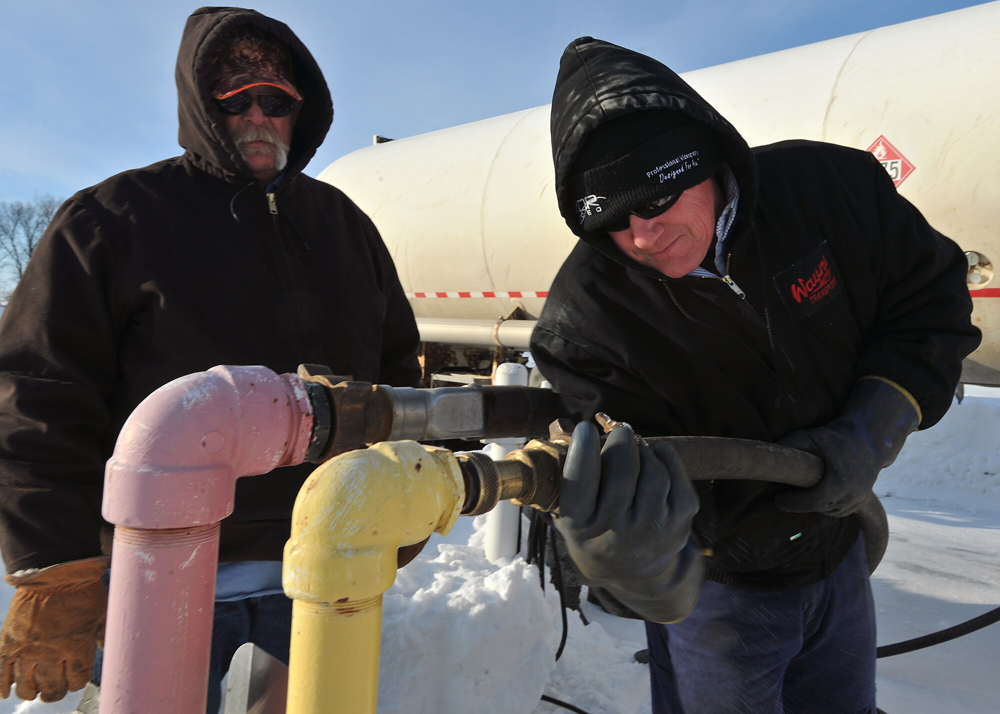 Kenneth Palm, 319th Civil Engineer Squadron heat ventilation and airconditioning technician (left), monitors Keneth Edman, Wayne Inc. Transports driver(right), as he tightens a hose to the base’s synthetic natural gas farm pipepline, Jan. 27, 2014 on Grand Forks Air Force Base, N.D. Edman was transporting nine thousand and two hundreed gallons of propane from Carrington Pipeline, N.D. to Grand Forks AFB, N.D. (U.S. Air Force photo/Senior Airman Xavier Navarro)