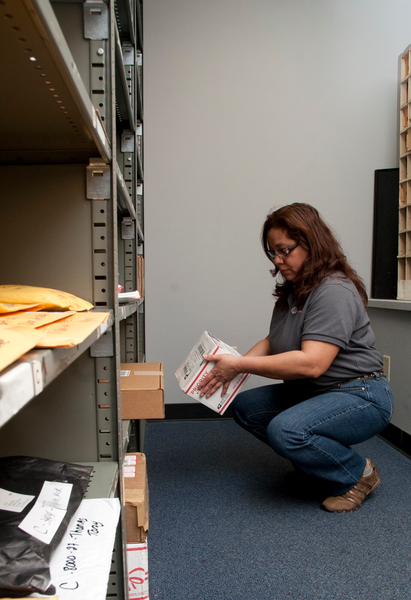 ALTUS AIR FORCE BASE, Okla. – Linda Colon, Principle Technologies Inc. employee manager, places a package on a shelf at the base U.S. Postal Service Center Jan. 29, 2014. Packages are held until the owner turns in a package slip. Slips are left inside individuals’ mailboxes that have packages waiting to be collected. (U.S. Air Force photo by Senior Airman Franklin R. Ramos/Released)