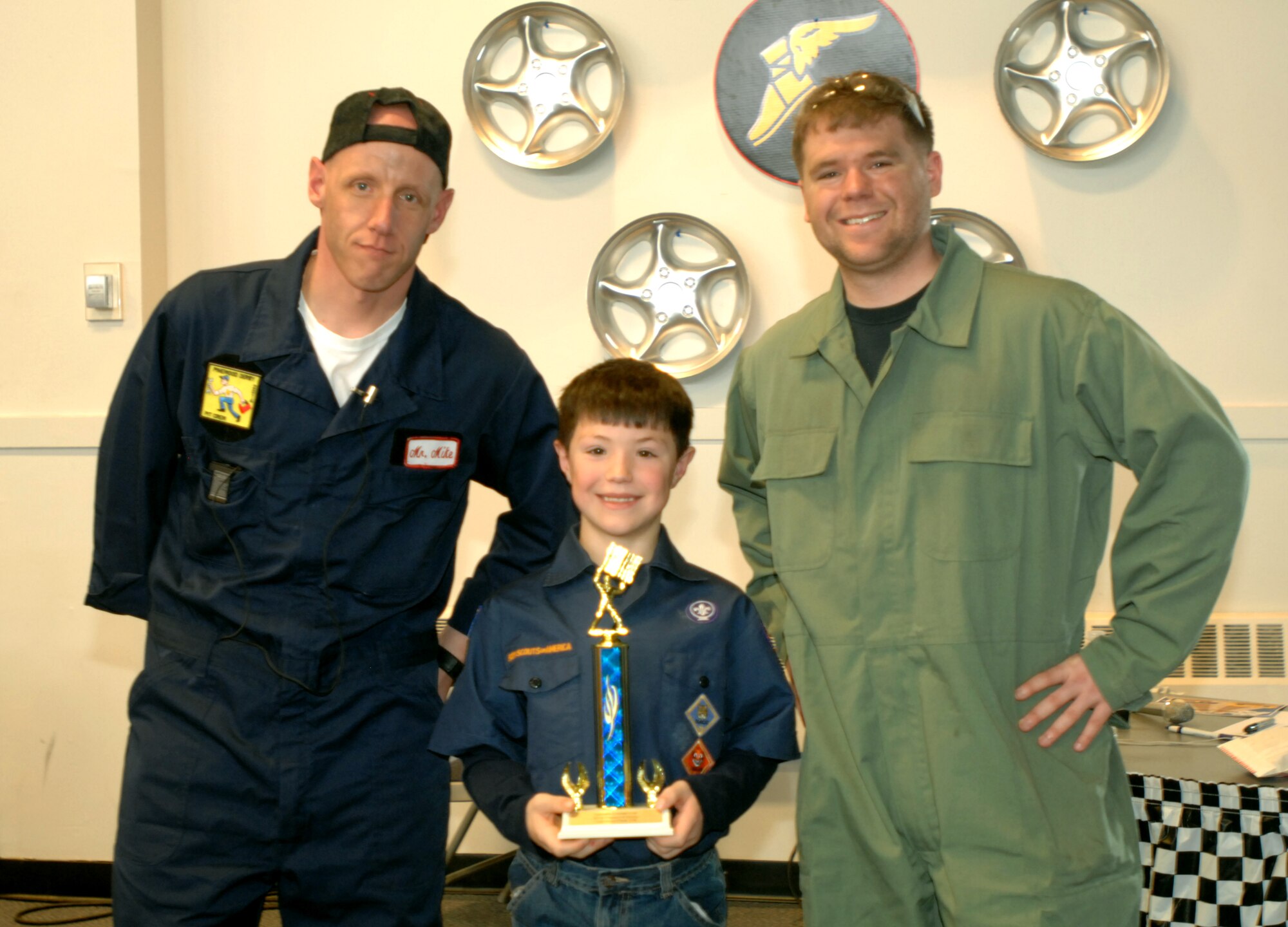 Senior Master Sgt. Michael Hermann (left), and Senior Airman Stephen Tice, 69th Maintenance Squadron, present the 2014 Cub Scouts Pinewood Derby Grand Champion trophy to Joshua Mumbulo, 8, Jan. 25, 2014, on Grand Forks Air Force Base, N.D. Contestants had the opportunity to win trophies for placing in the race, or being named fastest looking, most creative, best paint job, best craftsmanship, or Scouts’ choice. The pinewood derby is a Cub Scouts tradition that has been kept for more than 60 years. (U.S. Air Force photo/Staff Sgt. Susan L. Davis)
