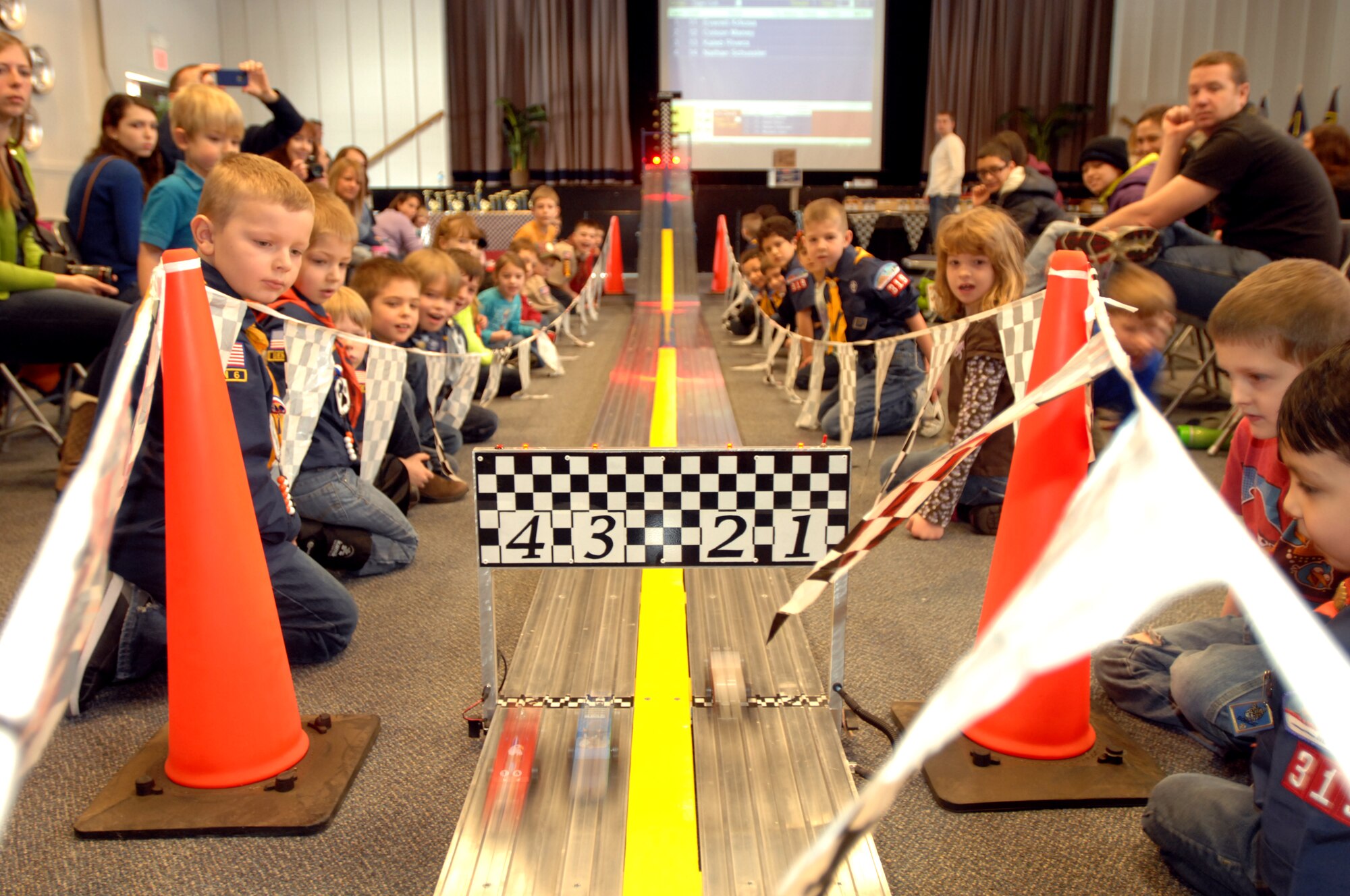 Children from Cub Scouts Pack 319 watch as pinewood cars race down the track at the 2014 Pinewood Derby Jan. 25, 2014 on Grand Forks Air Force Base, N.D. Contestants had the opportunity to win trophies for placing in the race, or being named fastest looking, most creative, best paint job, best craftsmanship, or Scouts’ choice. The pinewood derby is a Cub Scouts tradition that has been kept for more than 60 years. (U.S. Air Force photo/Staff Sgt. Susan L. Davis)