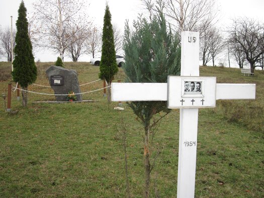 In the foreground the white wooden cross erected in 1990 by Vogelsberg, Germany Mayor Gerhard Harsch at the memorial site created to honor three American Airmen killed in a 1964 T-39 mishap over Erfurt, East Germany. The stone memorial seen in the background was placed at the site in 1998 by the citizens of Vogelsberg. A 50th anniversary memorial cerebration ceremony will be held at the site on Feb 2.  (Photo by Gerlinde Schmidt).