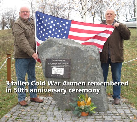 L to R:  Bernd Schmidt and Gerhard Harsch, the former mayor of Vogelsberg, Germany display the American flag at the memorial erected there in 1998 to honor three American Airmen killed in 1964 when their plane was shot down over Erfurt, East Germany. A 50th anniversary memorial cerebration ceremony will be held at the site on Feb 2. (Photo by Gerlinde Schmidt).
