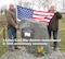 L to R:  Bernd Schmidt and Gerhard Harsch, the former mayor of Vogelsberg, Germany display the American flag at the memorial erected there in 1998 to honor three American Airmen killed in 1964 when their plane was shot down over Erfurt, East Germany. A 50th anniversary memorial cerebration ceremony will be held at the site on Feb 2. (Photo by Gerlinde Schmidt).