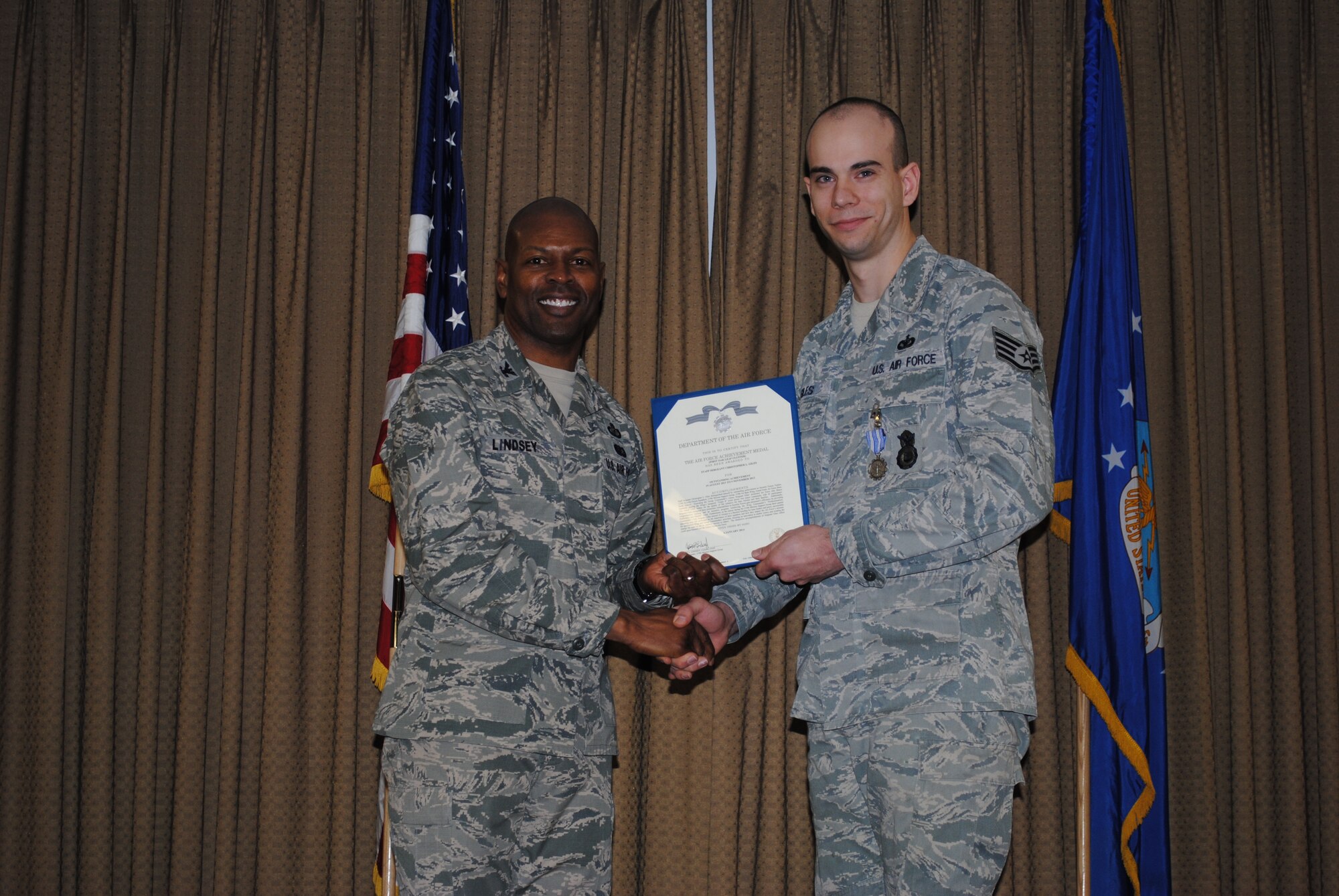 Col. Joe Lindsey, 319th Mission Support Group commander, congratulates 319th Security Forces Squadron training instructor, Staff Sgt. Christopher Giles, after being presented an Air Force Achievement Medal during a group commander’s call held Jan. 14, 2014, at the Northern Lights Club on Grand Forks Air Force base, N.D. Giles was selected as the recipient for Air Mobility Command’s Outstanding Support Staff NCO Award for 2013. (U.S. Air Force photo/Staff Sgt. Luis Loza Gutierrez) 