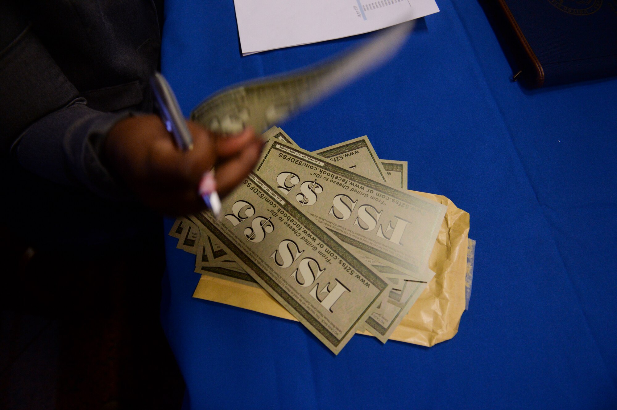 Allisa Shepard, 52nd Force Support Squadron Airman and Family Readiness Center work life specialist from Queens, N.Y., hands out FSS five-dollar bills prior to the start of the Caring For People Forum at Spangdahlem Jan. 29, 2014, at Spangdahlem Air Base, Germany. The FSS donated the money to the participants to help off-set the cost of their lunch. (U.S. Air Force photo by Senior Airman Rusty Frank/Released)