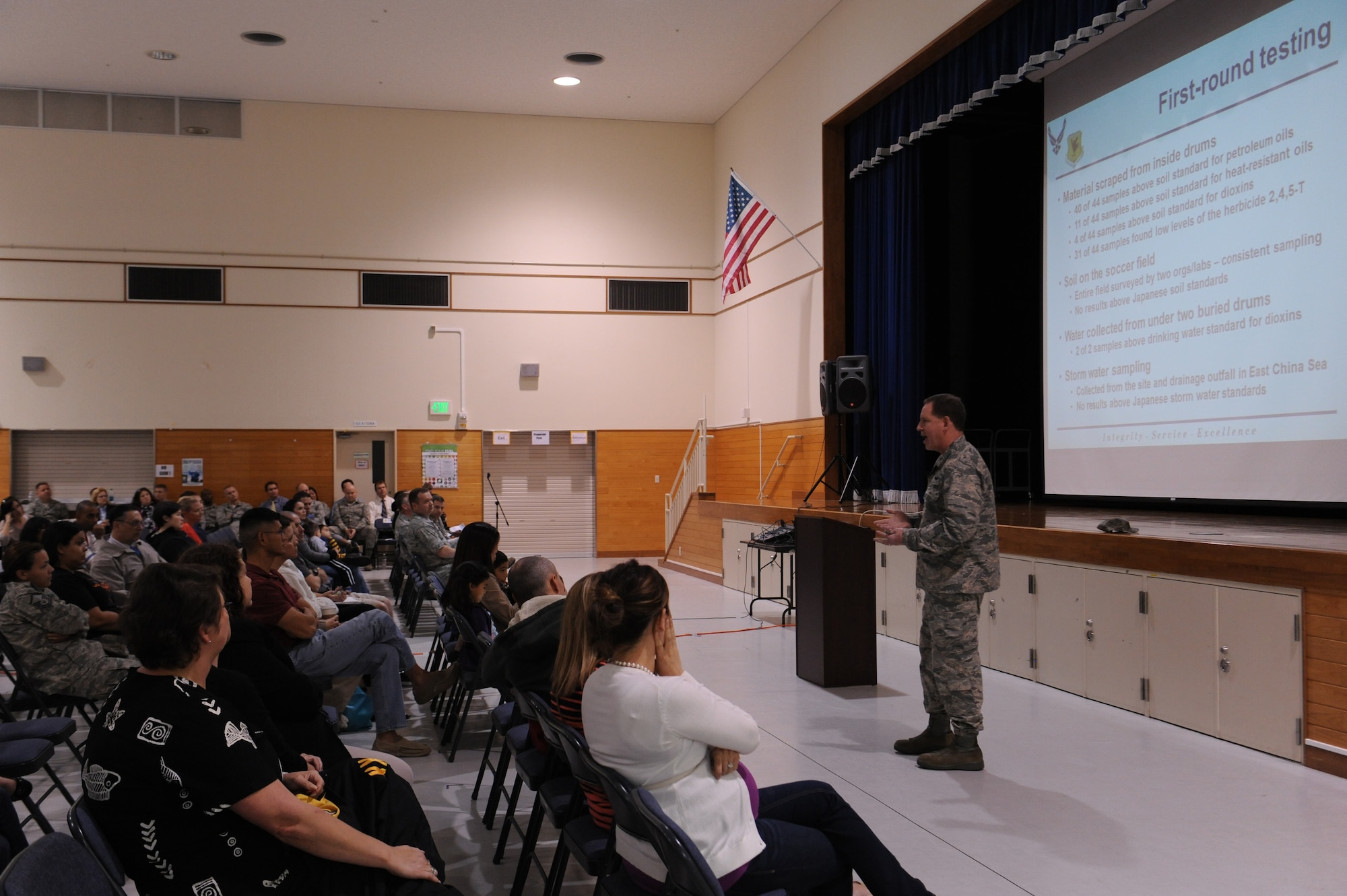 U.S. Air Force Brig. Gen. James Hecker, 18th Wing commander, briefs service members and community members on the discovery and excavation of 30-gallon barrels from the Okinawa City soccer field at a town hall meeting on Kadena Air Base, Jan. 28, 2014. The meeting was held to address concerns of local community members and discuss the area's safety, tests conducted on samples of soil, air and water, the history of the location and future actions. (U.S. Air Force photo by Senior Airman Malia Jenkins)