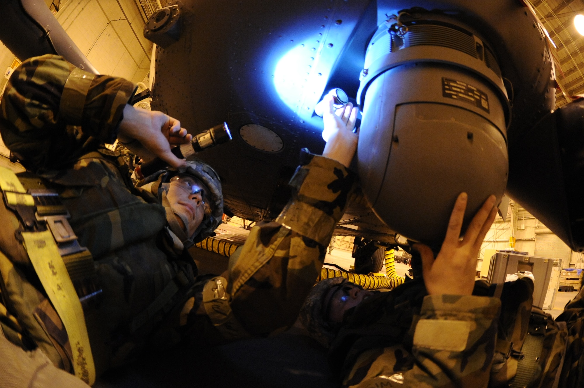 U.S. Air Force Senior Airman Eric Sperry, 33rd Helicopter Maintenance Unit integrated flight control specialist (left), and Senior Airman Joshua Whiting, 33rd HMU communications and navigation system technician, install a turret forward-looking infrared unit cable onto an HH-60G Pave Hawk helicopter on Kadena Air Base, Japan, Jan. 30, 2014. The Pave Hawk, capable of maneuvering and operating in almost any environment, is primarily used for search and rescue missions. (U.S. Air Force photo by Airman 1st Class Keith James)