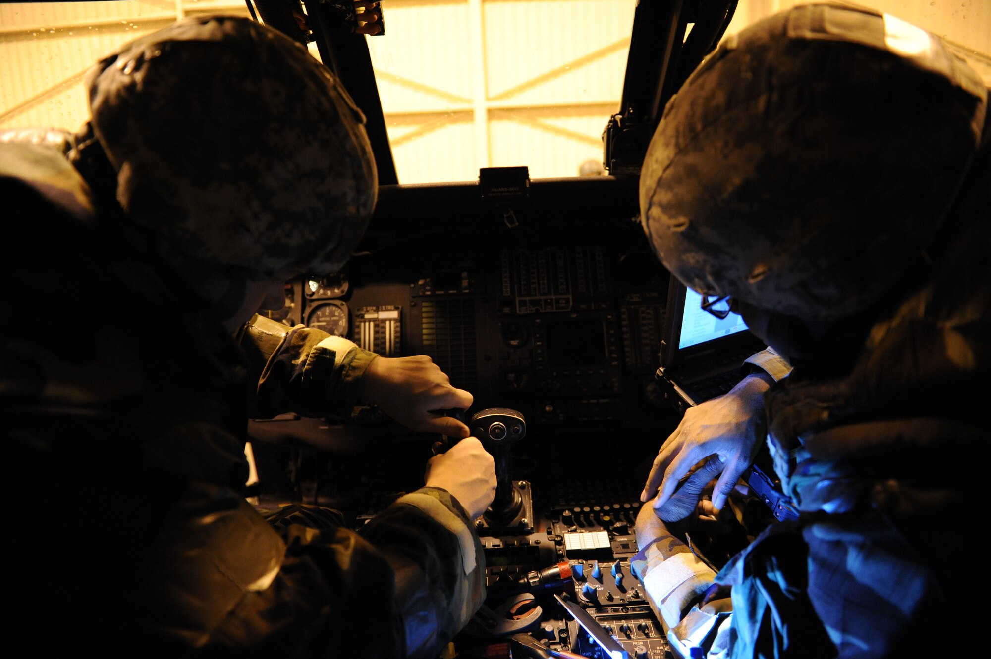 U.S. Air Force Staff Sgt. Phillip Buchsbaum (left) and Airman 1st Class Kamar Morrison, both 33rd Helicopter Maintenance Unit communications and navigation technicians, reinstall a multi-function control unit in the cockpit of an HH-60G Pave Hawk helicopter on Kadena Air Base, Japan, Jan. 30, 2014. The HH-60 is capable of performing civil search and rescue, emergency aeromedical evacuation, disaster relief and international aid. (U.S. Air Force photo by Airman 1st Class Keith James)