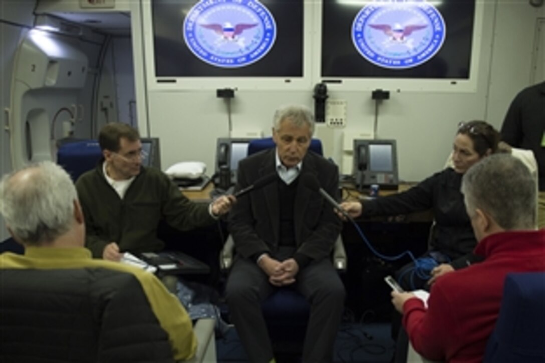 U.S. Defense Secretary Chuck Hagel, center, hosts a press briefing aboard his plane en route to Europe to meet with defense leaders and to attend the 50th Munich Security Conference, Jan. 29, 2014.