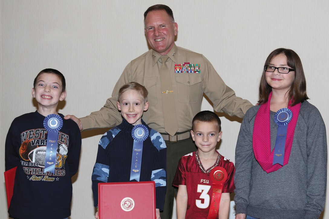 Maj. Gen. John J. Broadmeadow, commanding general, Marine Corps Logistics Command, presents certificates to Holiday Safety Poster winners during a ceremony held here, recently.
