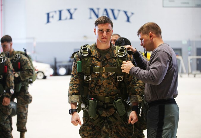 Sgt. David Tanney, the jump team leader with Bravo Company, 3rd Reconnaissance Battalion, 3rd Marine Division, gets his gear checked over in Hangar 105 before conducting high-attitude high-opening parachuting during Exercise Sandfisher, Jan. 28, 2014. The reconnaissance Marines jumped twice a day from a Lockheed C-130 Hercules aircraft, practicing skills and developing the correct methods and tactics while working as a team. (U.S. Marine Corps photo by Lance Cpl. Suzanna Knotts)
