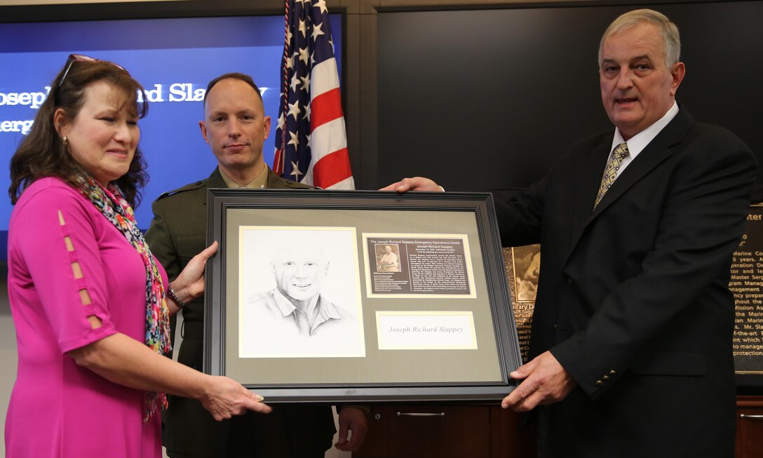 Connie Slappey, Col. Chris Pappas III and James Riemer present a hand-drawn picture of Joseph ‘Richard’ Slappey during a dedication ceremony in his honor at the Emergency Operations Center Jan. 25. Connie is the wife of the late Richard Slappey, Pappas is the commanding officer of Marine Corps Air Station Cherry Point and James Riemer is the director of air station operations.