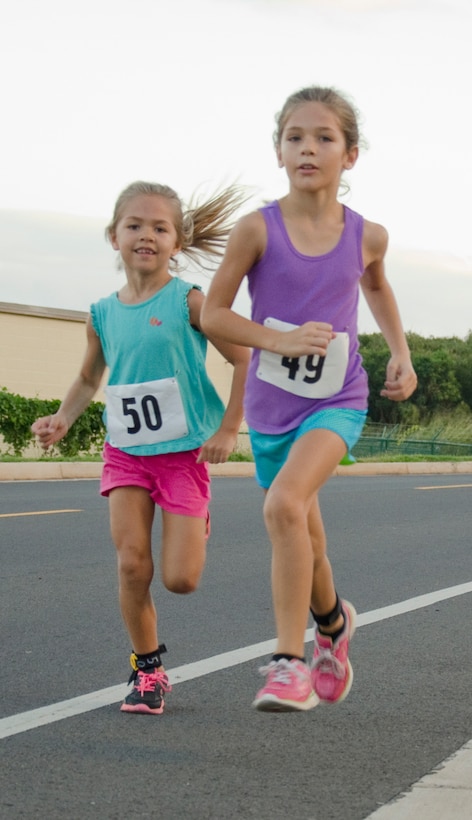 Isabella (left) and Madison Van Buren run down Reed Road during the King of the Hill race, Jan. 25, 2014. King of the Hill is a 5-kilometer run starting and ending at Dewey Square, taking participants up Kansas Tower Hill. King of the Hill is one of 12 races in the Commanding Officer’s Fitness Series this year. (U.S. Marine Corps photo by Kristen Wong)