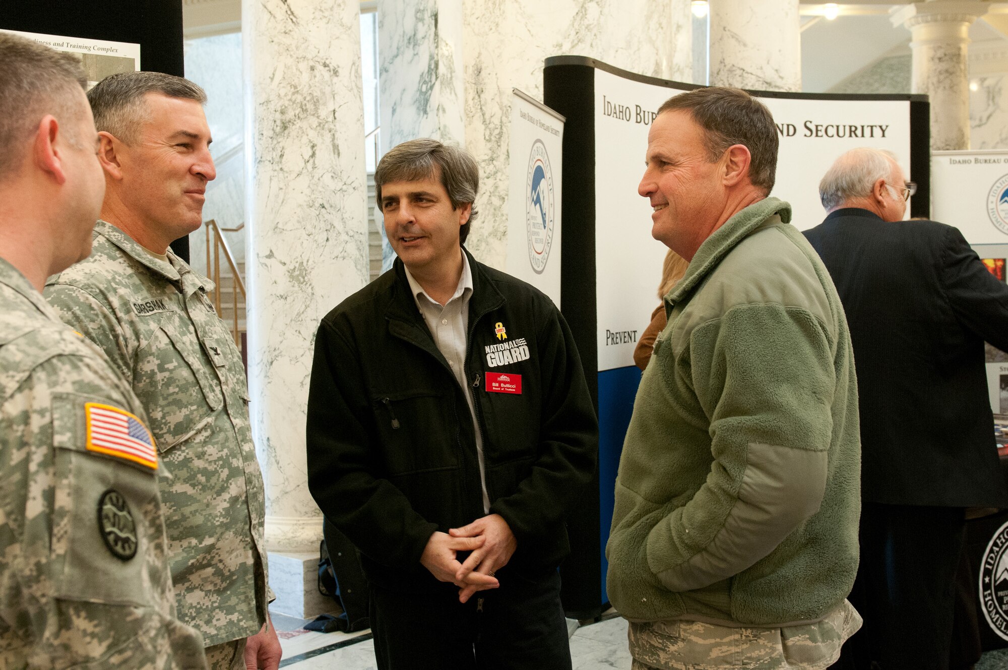 Bill Butticci, a member of the Board of Trustees, talks with Brig. Gen. Richard Turner, right, Assistant Adjutant General, Air, and Col. Michael Garshak, left, Director of Operations from the Idaho Army National Guard, regarding a display about construction for future facilities and the economic impact contributing to the economy during the Military Division Legislative Day held at the State Capitol building in Boise, Idaho Jan. 15. (Air National Guard photo by Master Sgt. Becky Vanshur)