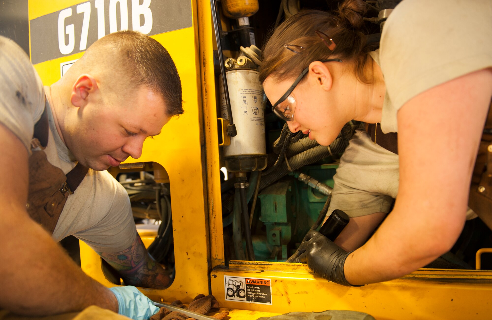 Staff Sgt. Robert Sommerfeldt and Airman 1st Class Johanna Desimone, 5th Logistics Readiness Squadron vehicle mechanics, replace a part on a tractor at Minot Air Force Base, N.D., Jan. 28, 2014. Vehicle mechanics are responsible for the maintenance of all the government-owned vehicles on base. (U.S. Air Force photo/Airman 1st Class Apryl Hall)