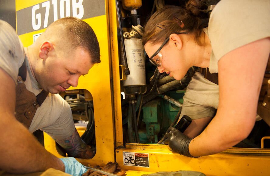 Staff Sgt. Robert Sommerfeldt and Airman 1st Class Johanna Desimone, 5th Logistics Readiness Squadron vehicle mechanics, replace a part on a tractor at Minot Air Force Base, N.D., Jan. 28, 2014. Vehicle mechanics are responsible for the maintenance of all the government-owned vehicles on base. (U.S. Air Force photo/Airman 1st Class Apryl Hall)