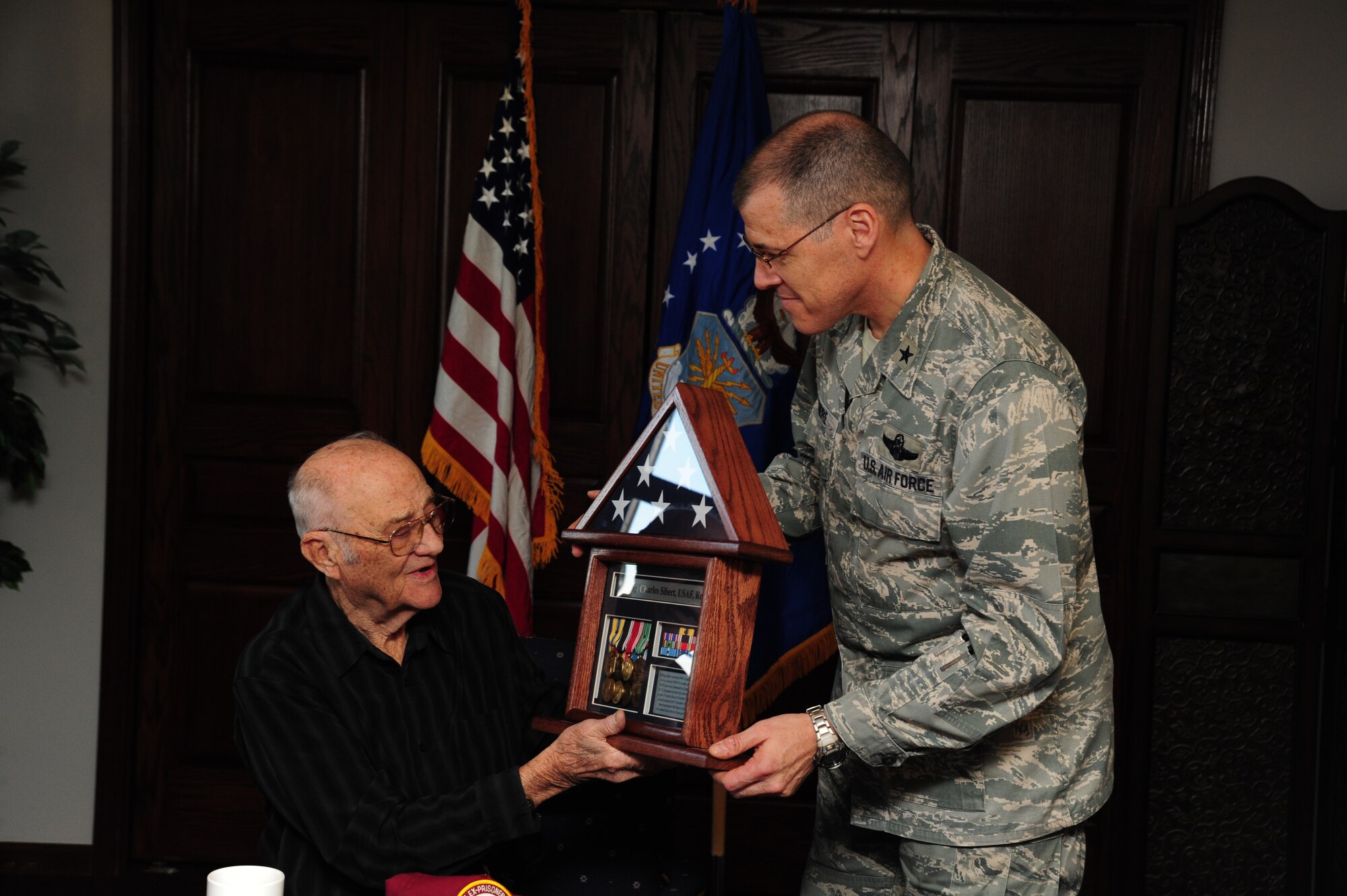 Brig. Gen. Thomas A. Bussiere, 509th Bomb Wing commander, presents a shadow box to retired Chief Master Sgt. Charles Sibert, 8th Air Force World War II veteran, at Whiteman Air Force Base, Mo., Jan. 24, 2014. Sibert was held in a prisoner of war camp during WWII for more than 500 days. (U.S. Air Force photo by Staff Sgt. Nick Wilson/Released)