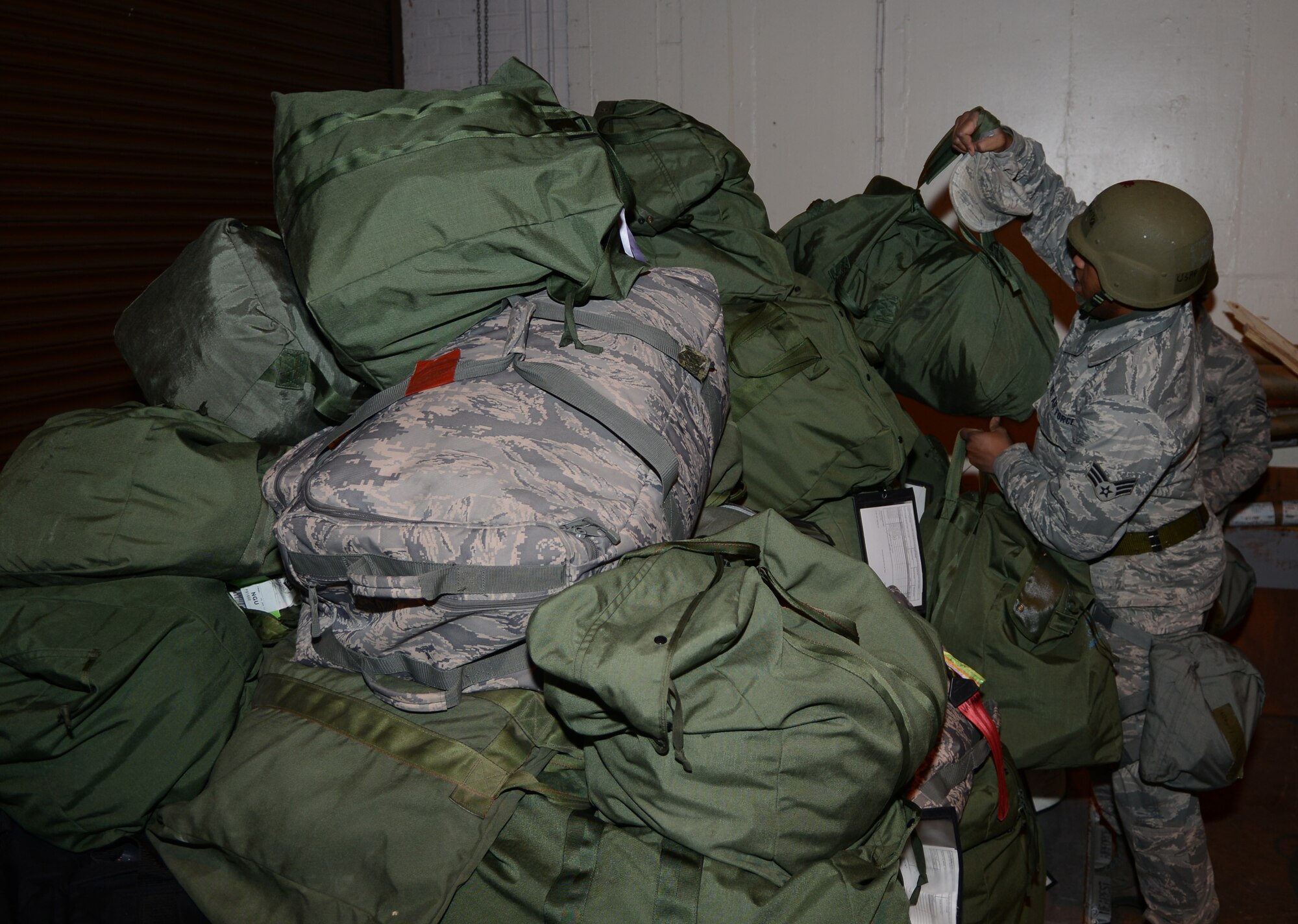 A Team Mildenhall member piles mobility bags onto a pallet Jan. 30, 2014, during a deployment exercise on RAF Mildenhall, England. Mobility bags contain essential gear for downrange operations such as Mission Oriented Protective Posture gear. The exercise, part of a base-wide operational readiness inspection, focused on assessing the base’s preparedness for real-world operations. (U.S. Air Force photo by Airman 1st Class Dillon Johnston/Released)