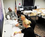 From back to front: Maj. Alfred Doby, 359th Aerospace Medical squadron bioenvironmental engineering flight commander, Tech. Sgt. Jean Museau, 359th AMDS NCO in charge of bioenvironmental engineering, Capt. Bernardo Garcia, 359th AMDS officer in charge of environmental health, and Shea Peters, 359th AMDS Health Promotions program coordinator, review inspection preparation material Jan. 24 at the Joint Base San Antonio-Randolph medical clinic. (U.S. Air Force photo by Airman 1st Class Alexandria Slade)