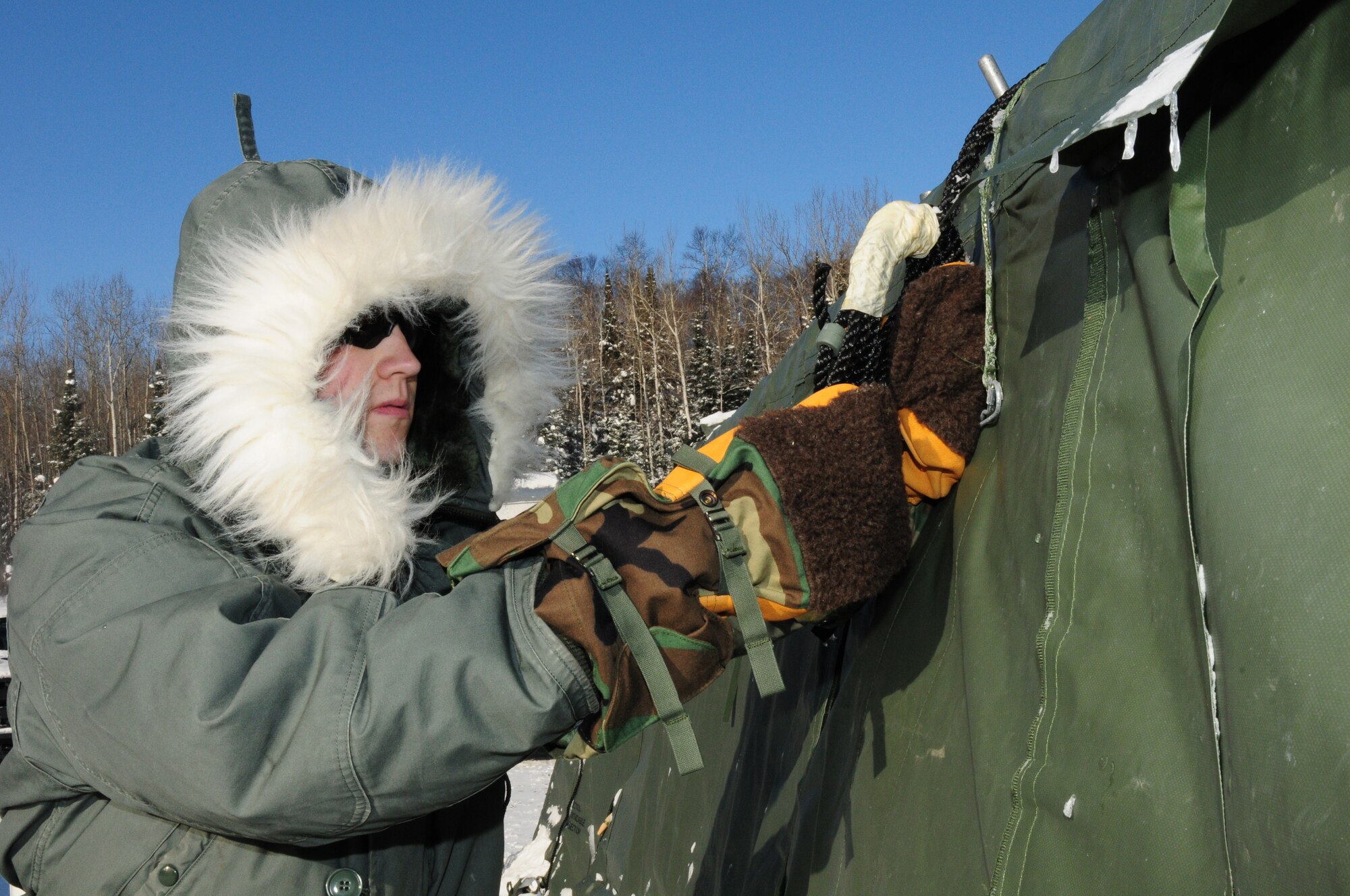 U.S. Air Force Staff Sgt. Eric Ronning, a member of the Deployable Interoperable Communications Element (DICE) team, 148th Fighter Wing, Duluth, Minn. performs a safety check on a tent while at a remote location northwest of Grand Marais, Minn., Jan. 28, 2014.  Staff Sgt. Ronning and the DICE team were at the remote location to provide communication support for the John Beargrease sled dog marathon.  (U. S. Air National Guard photo by Master Sgt. Ralph J. Kapustka/Released)  