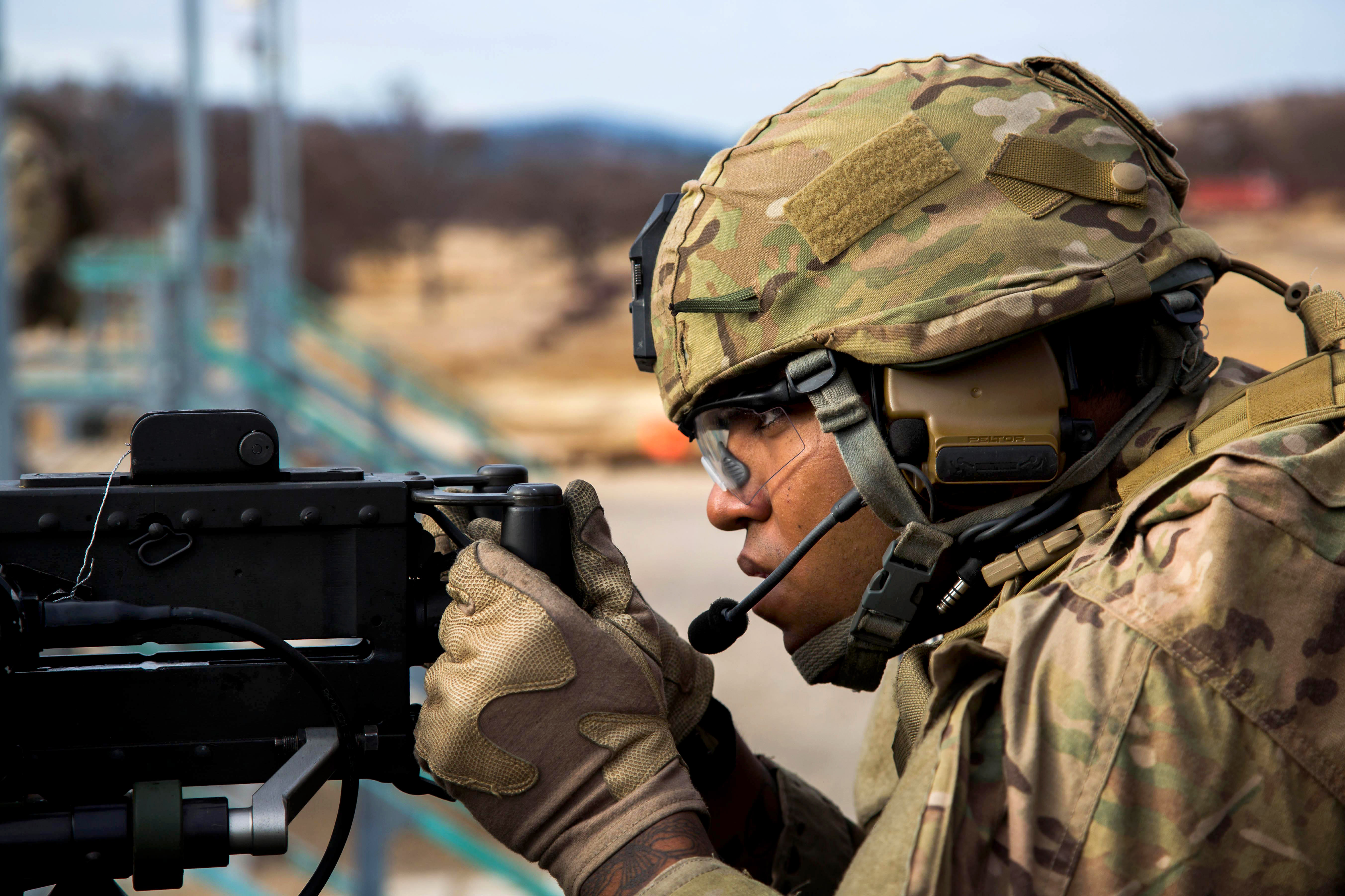 An Army Ranger fires a .50-caliber machine gun mounted on a Stryker ...